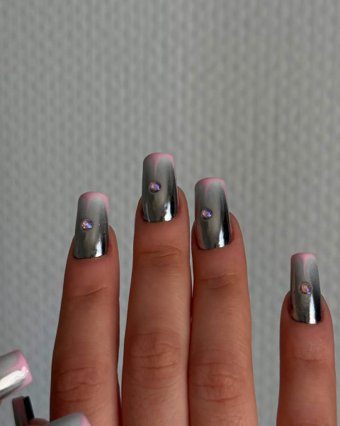 Nails straight up in the air with a gray metallic base a pink French tip and jewel in the middle.