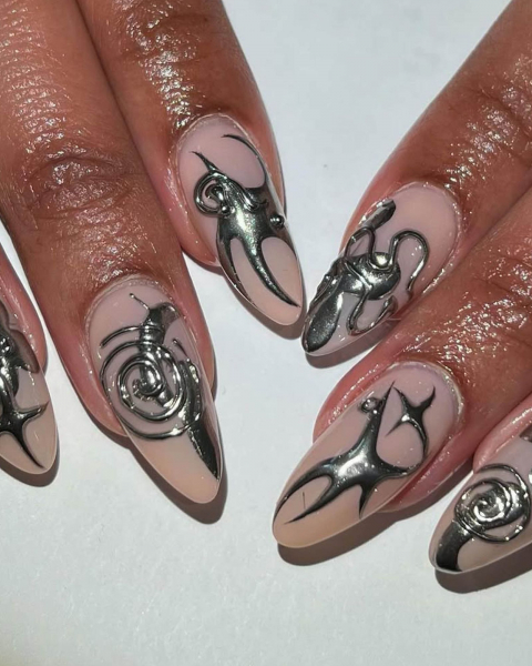 A closeup of fingers laying flat featuring silver puffy icons on nude nails.