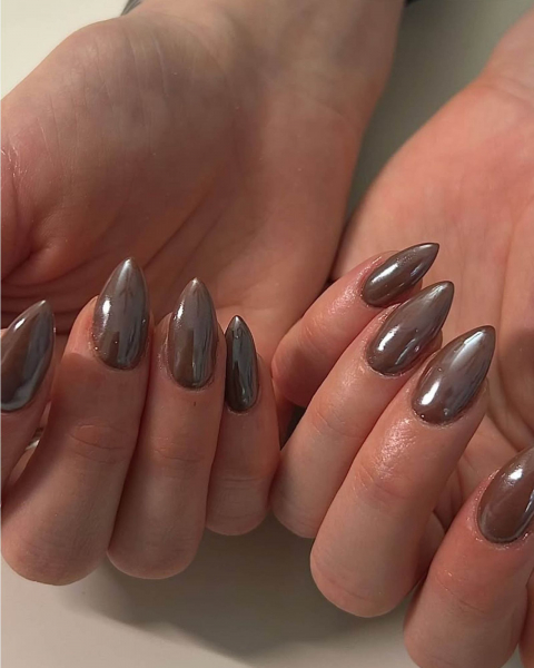Hands with fingers curling upwards showing long brown nails.