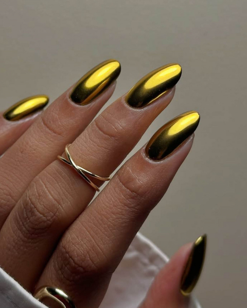 Hand coming out from a white sleeve featuring rings and yellow metallic nails.