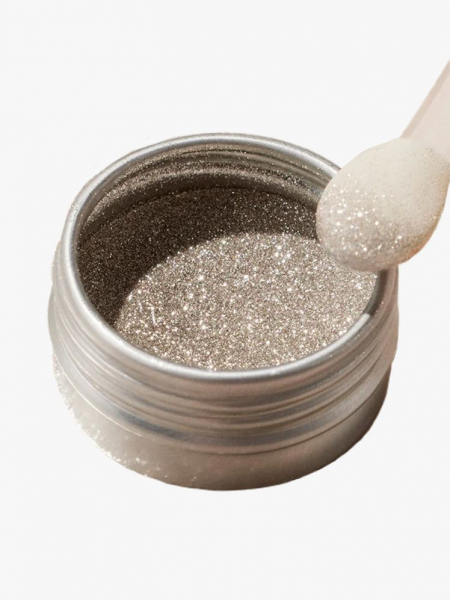 Glittery powder in a metal container, being swabbed by a cotton pad.